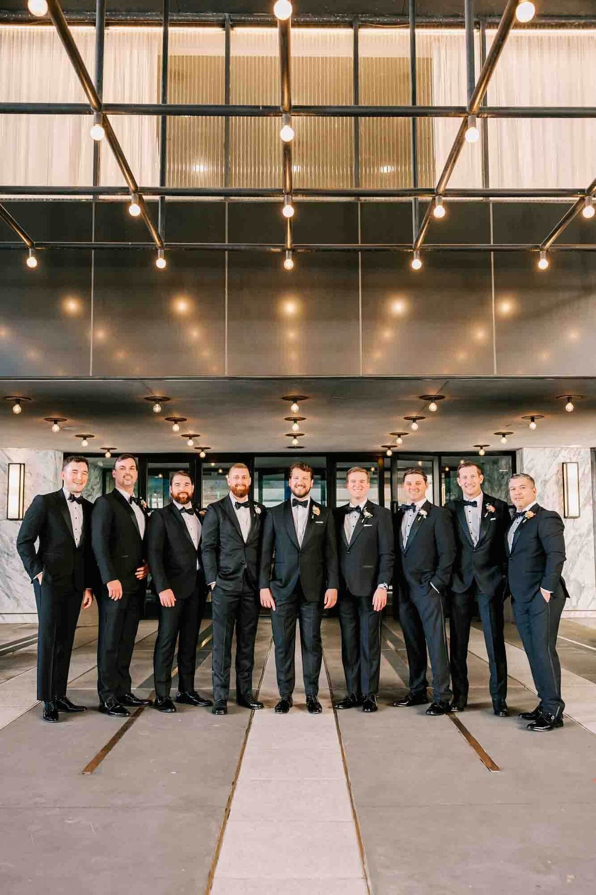 groom and his groomsmen stand under the lit carport at the four seasons hotel for a chic portrait