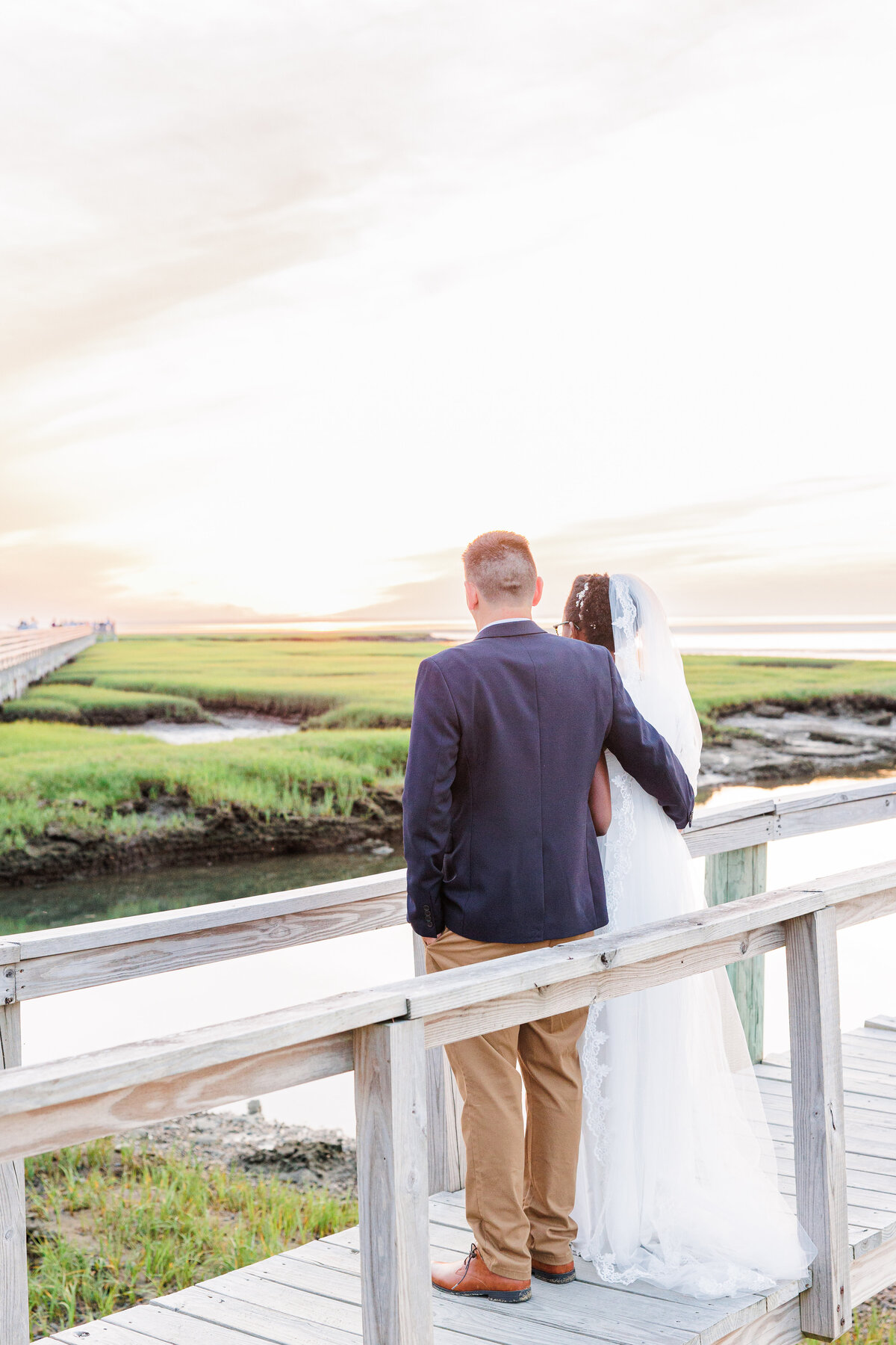 Bride and groom looking at the sunset at Bass Hole Boardwalk during Cape Cod wedding portraits