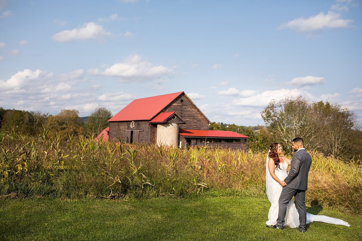 Bride and groom holding hands in front of a barn.