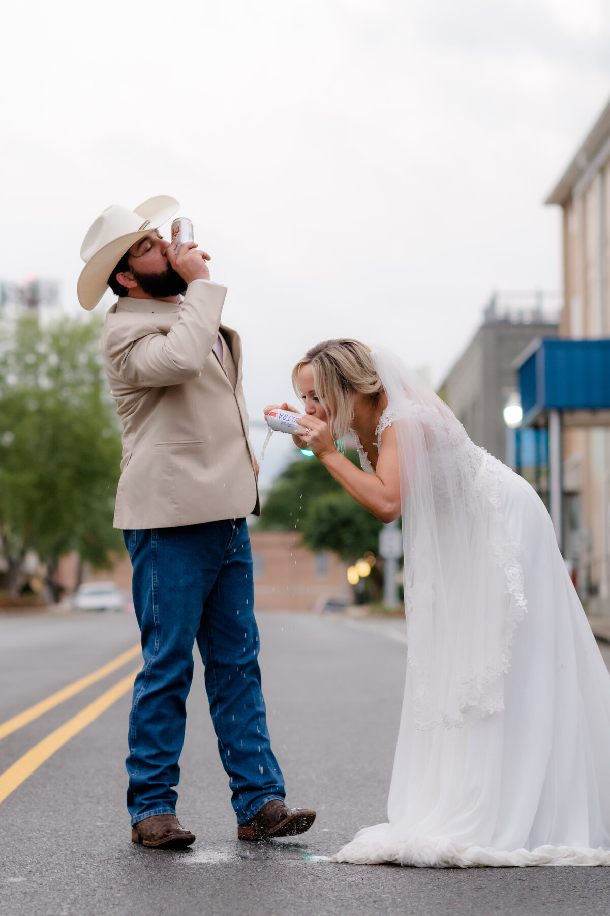 bride adn groom shot gunning a beer together in the middle of the road together for their bridal session