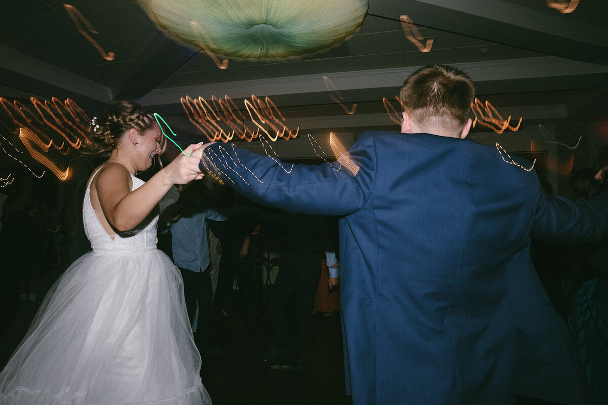 Color candid of bride twirling in her dress while groom watches.