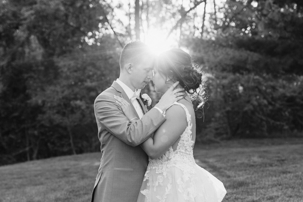 black and white photo of a couple with their arms around each other about to kiss