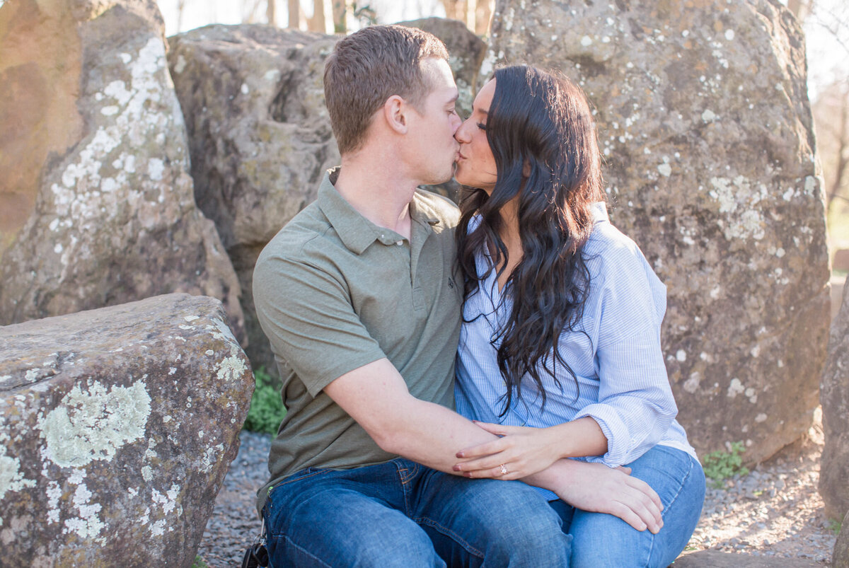 A just engaged couple kiss, seated on a rocky overlook near Boulder Colorado