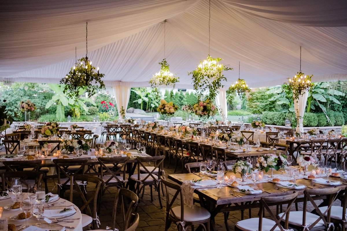 Romantic garden tent wedding with greenery covered chandeliers.