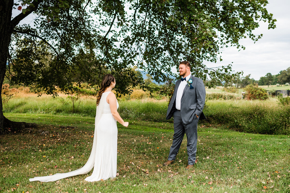 grooms reaction to his first look at his bride under a large oak tree at Shenandoah wedding venue