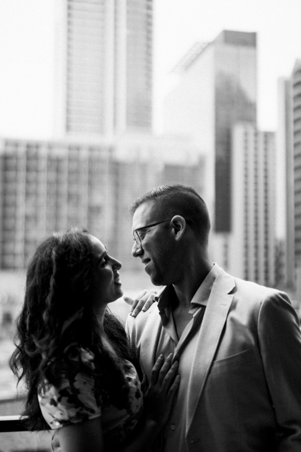 Couple embrace in front of buildings