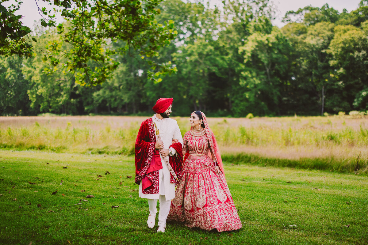 Indian bride and groom walking across the grass on their wedding day at natirar park in bridgewater nj