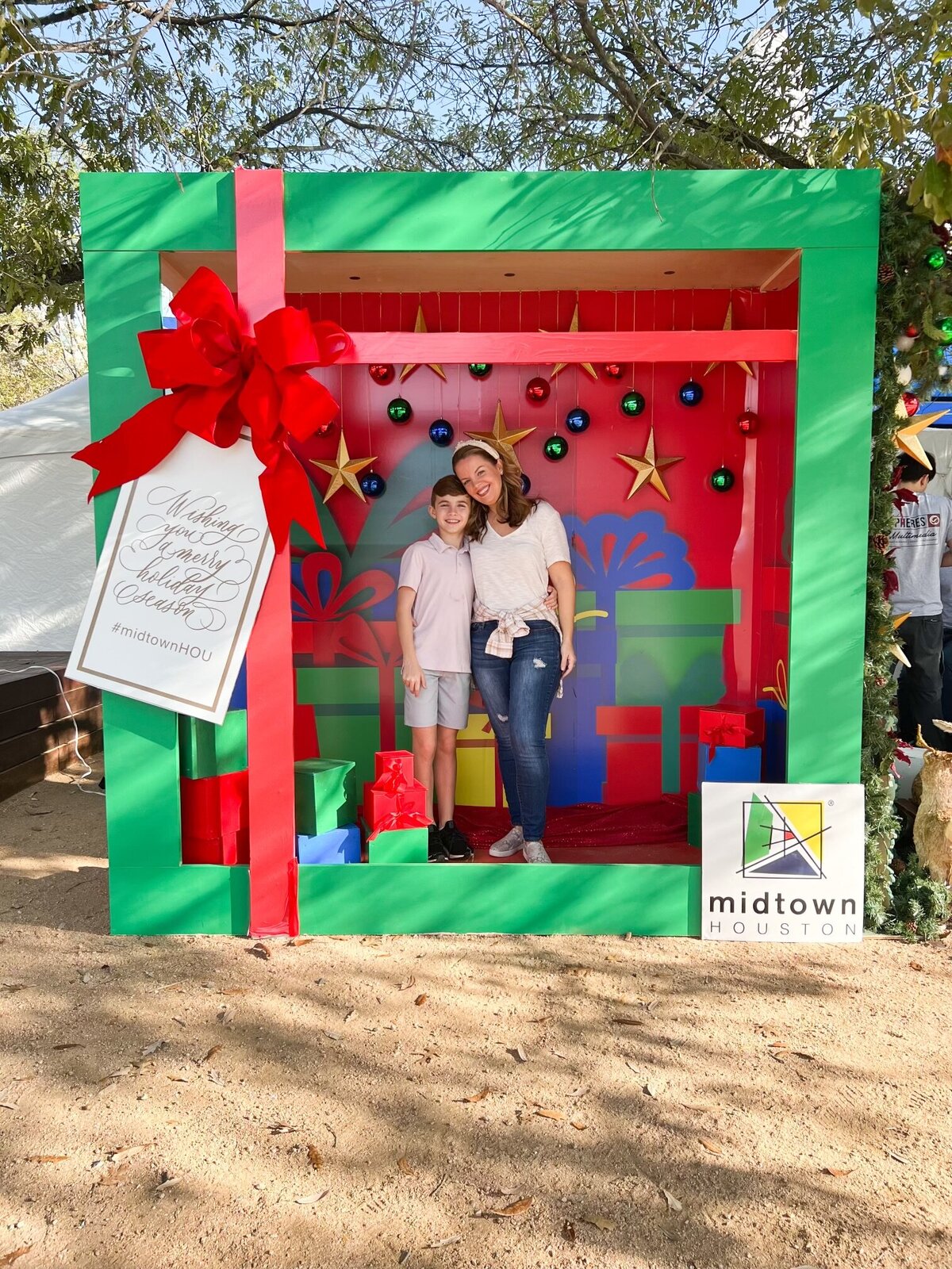 Mother and son posing in a present shaped holiday photo booth backdrop at a Midtown Houston corporate event