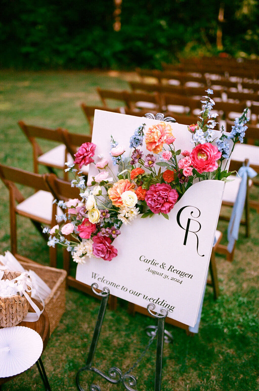 A wedding welcome sign with flowers and chairs in the background at an Oregon outdoor wedding.