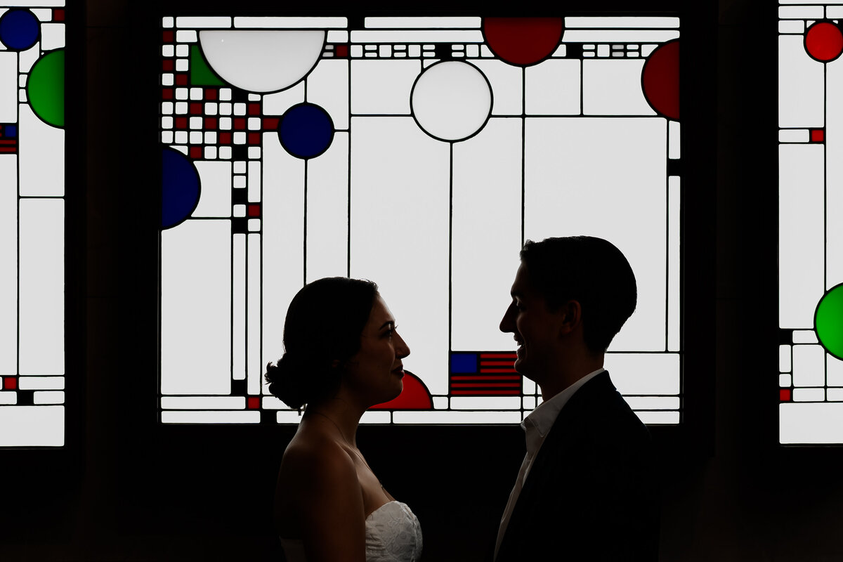A couple look at each other in front of an art piece.