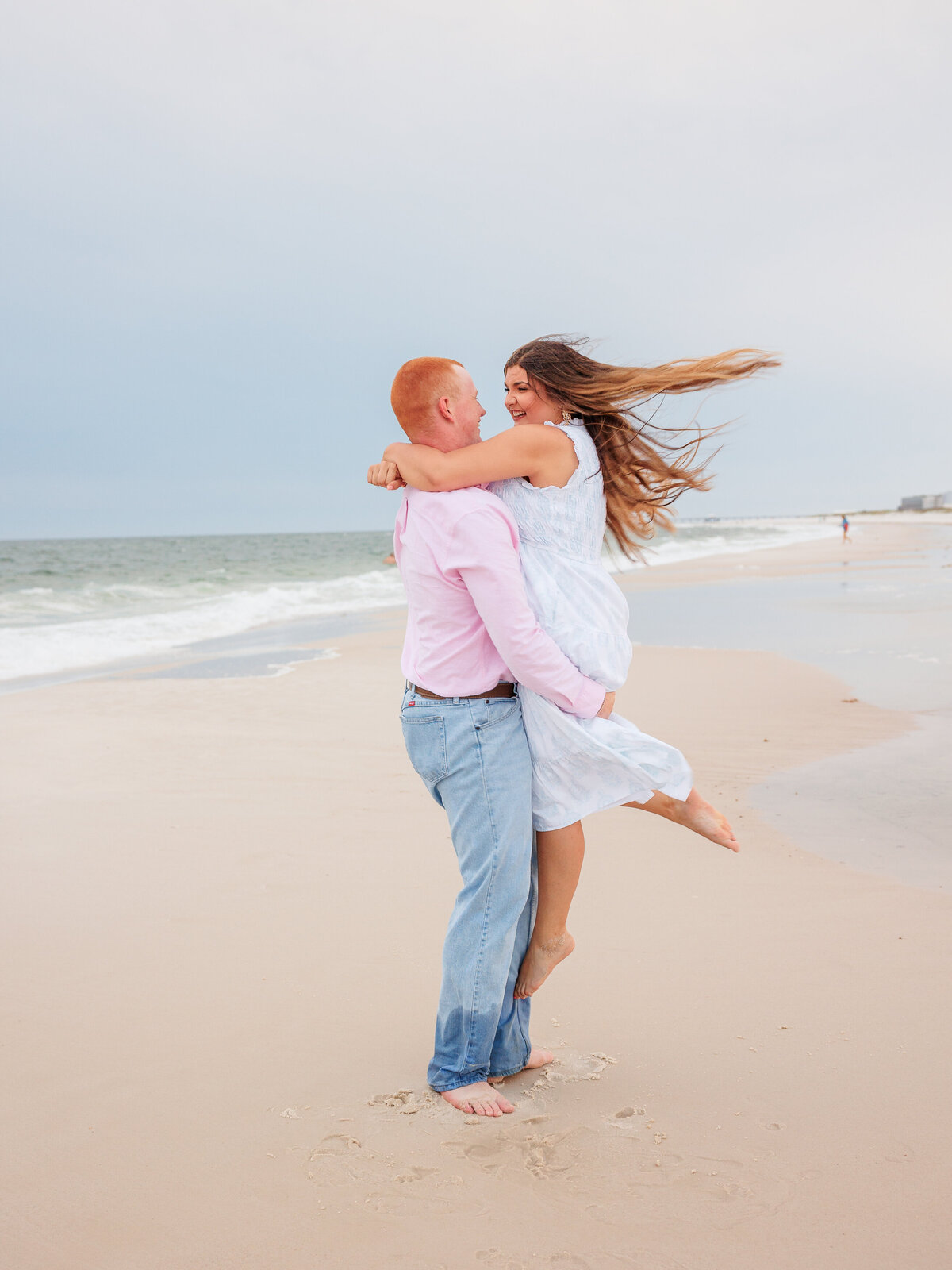 New couple laughing as they spin along the shoreline in Gulf Shores