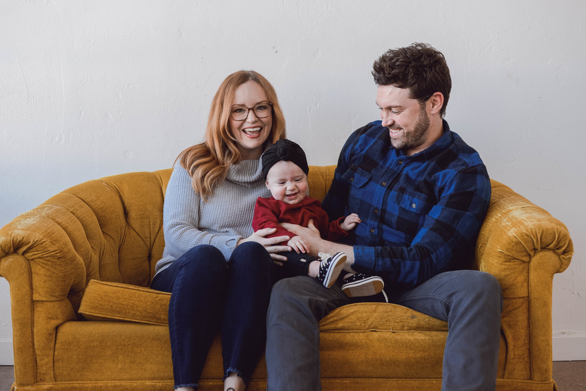 mom, dad and baby on yellow couch at the Denver photo collective