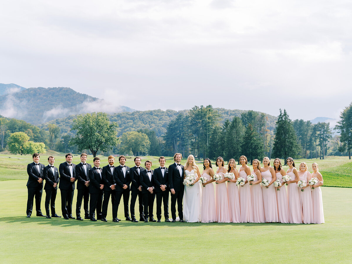 Large wedding party standing on the golf course with mountain backdrop at The Waynesville Inn & Golf Club wedding in Waynesville, NC.