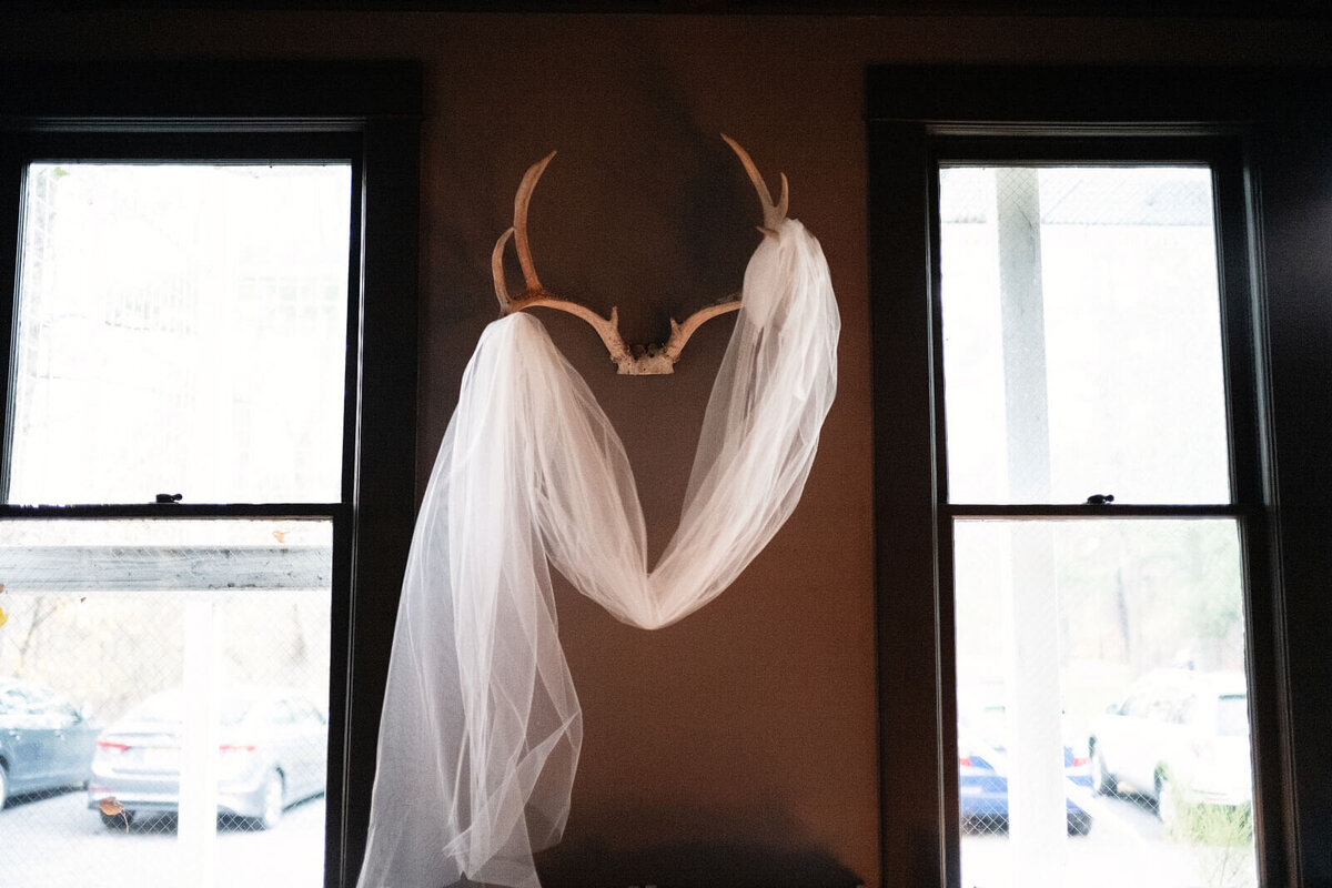 The bride's veil is hung on a wall décor inside a room in Foxfire Mountain House, New York. Wedding Image by Jenny Fu Studio