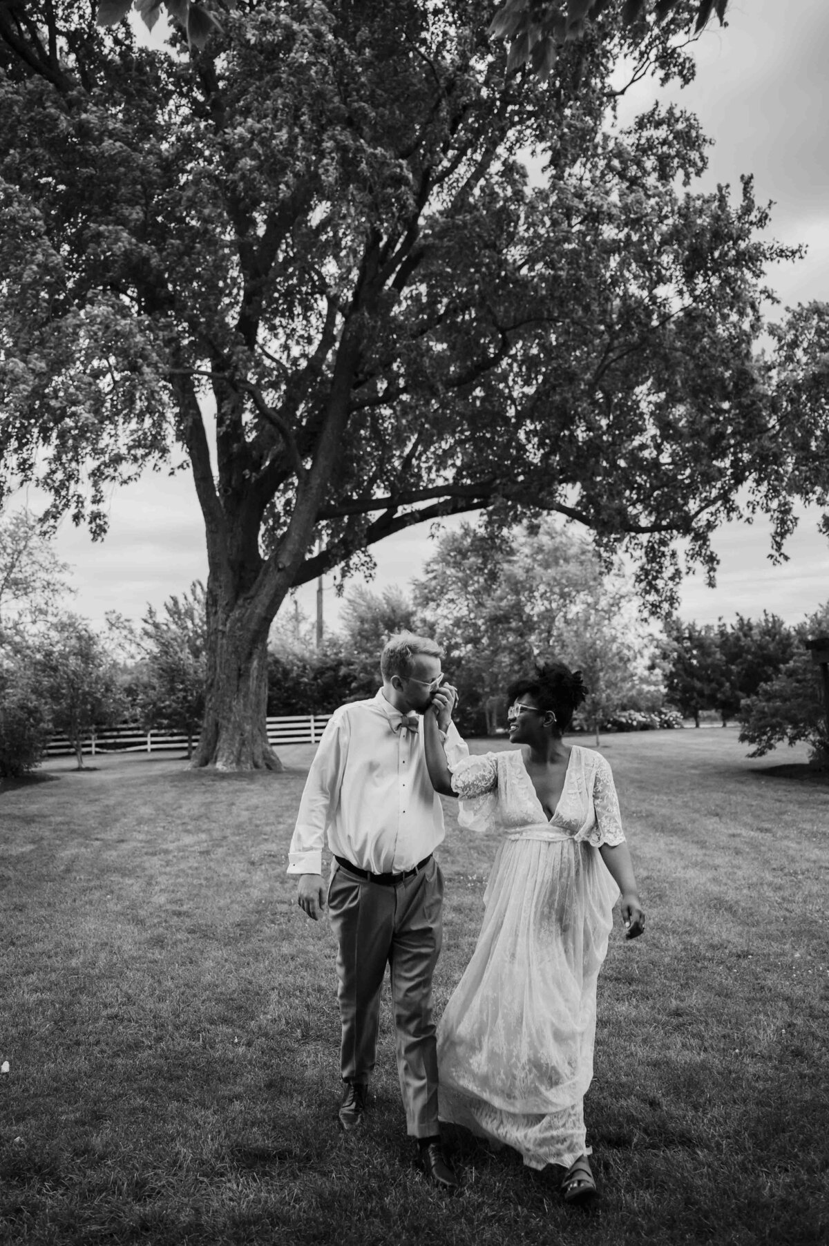 Bride and groom walk in front of big Oak tree