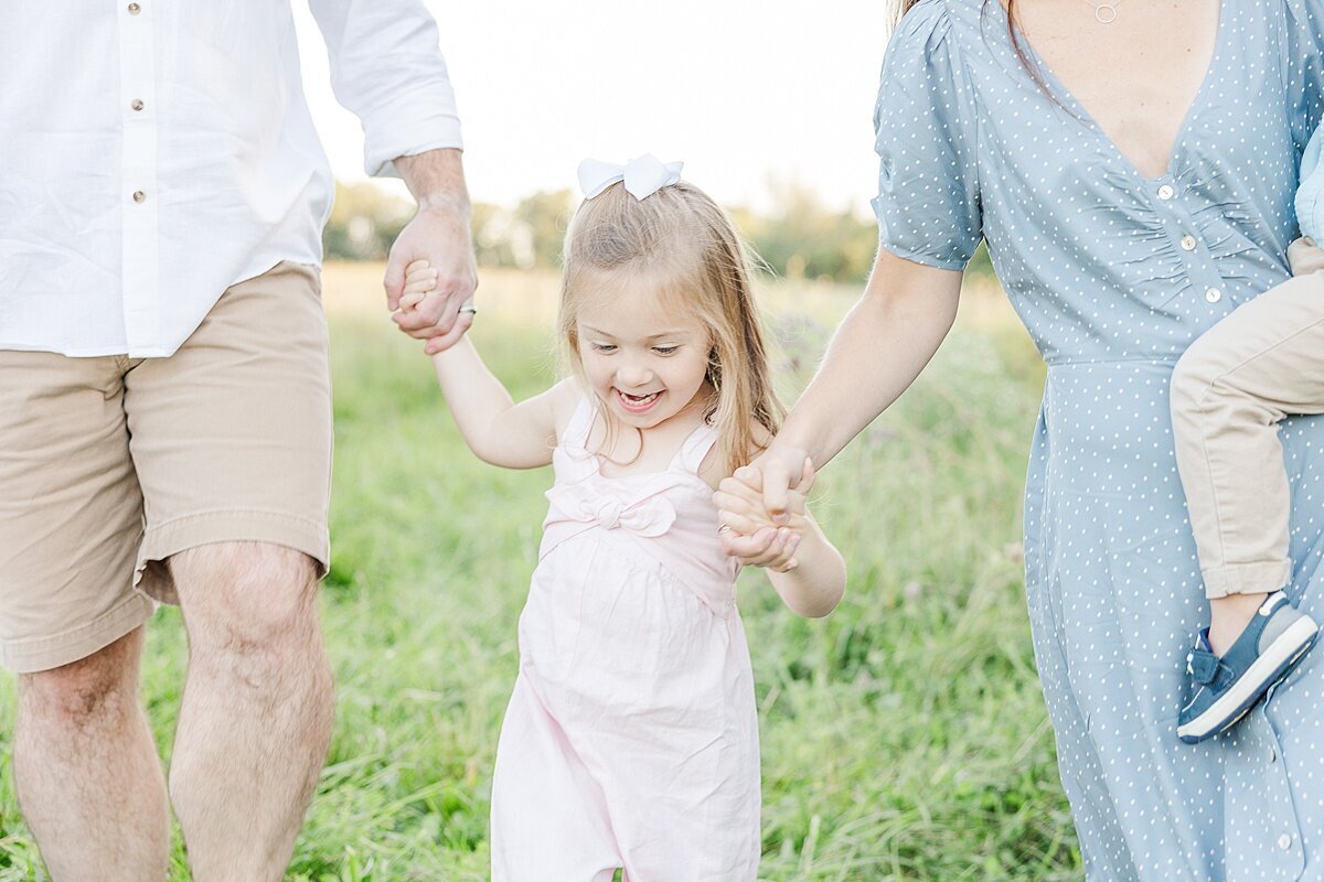 paren ts hold girls hand duirng fall family photo session with Sara Sniderman Photography in Natick Massachusetts