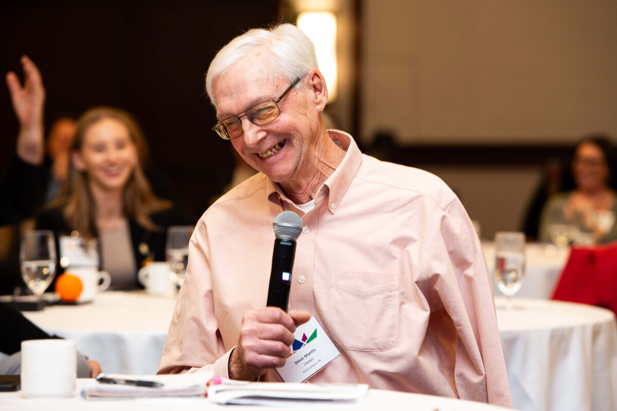 Ottawa event photography showing a man smiling and laughing into a microphone during a corporate conference. Captured by JEMMAN Photography COMMERCIAL 