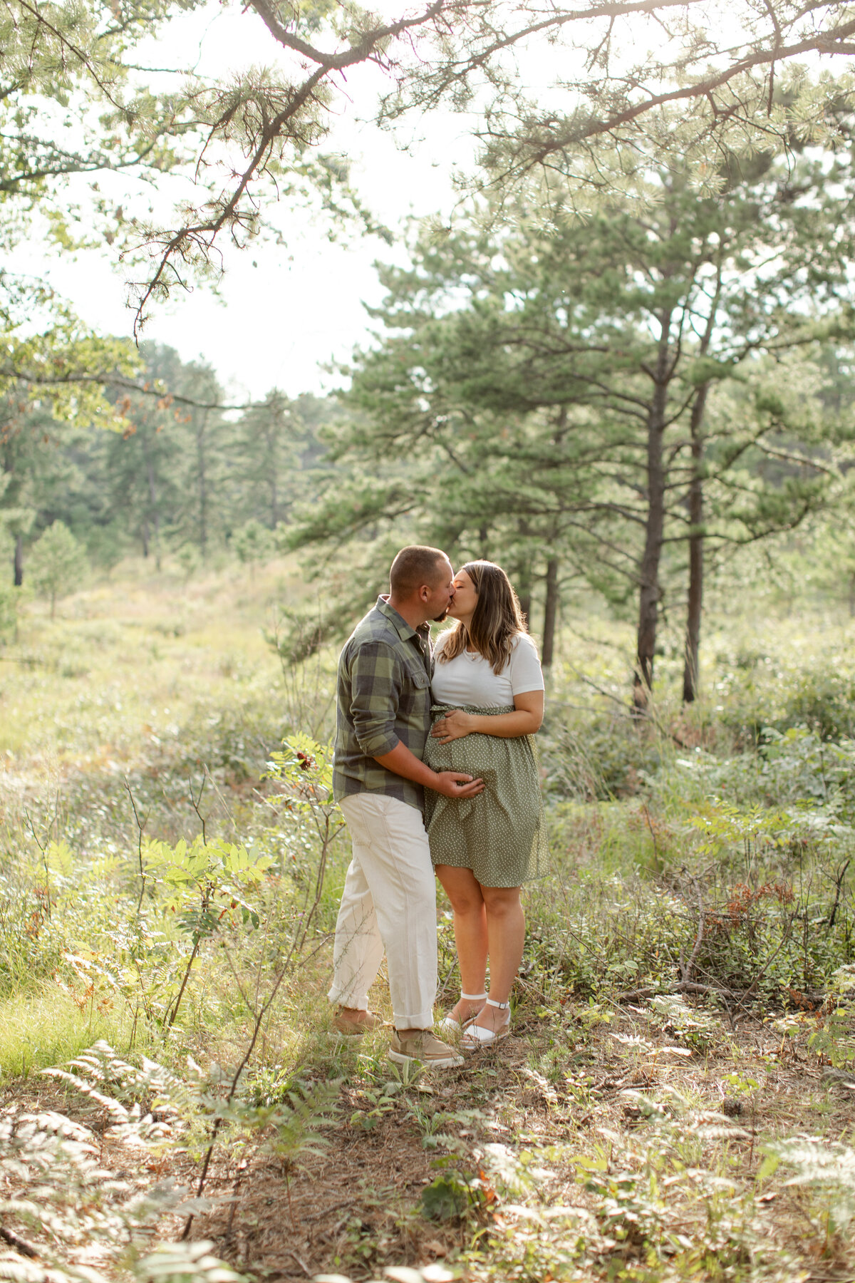 Pregnant couple kiss in a field