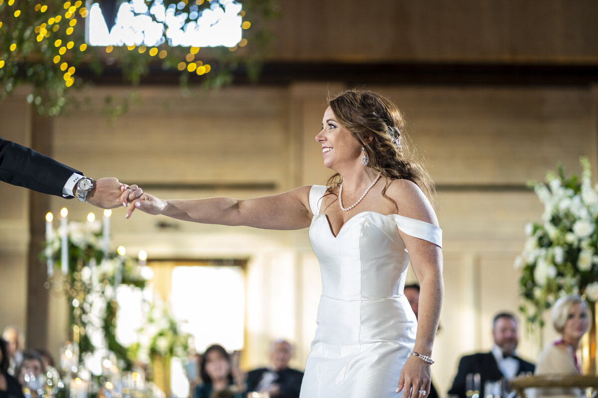 Bride holding grooms hand mid dance.