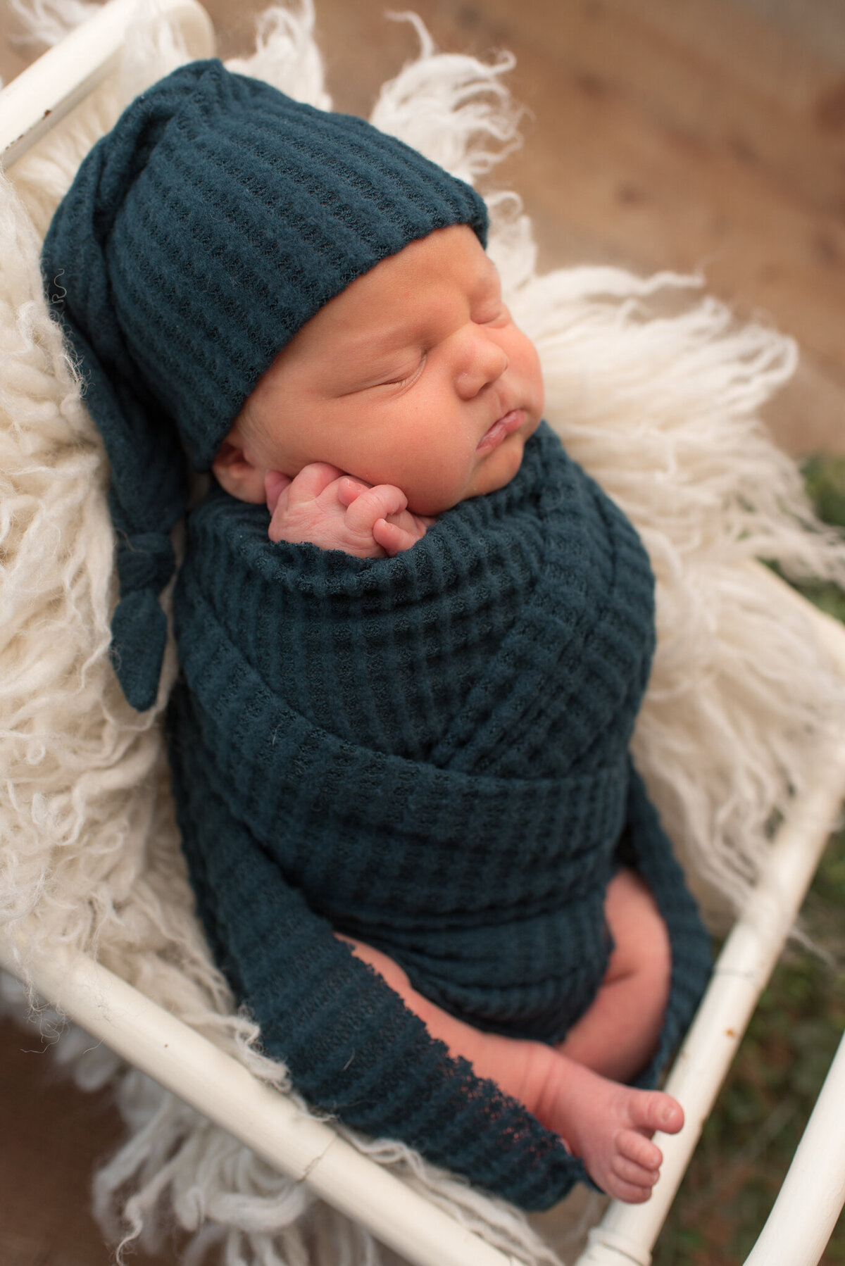 Baby boy wrapped in teal in white crib