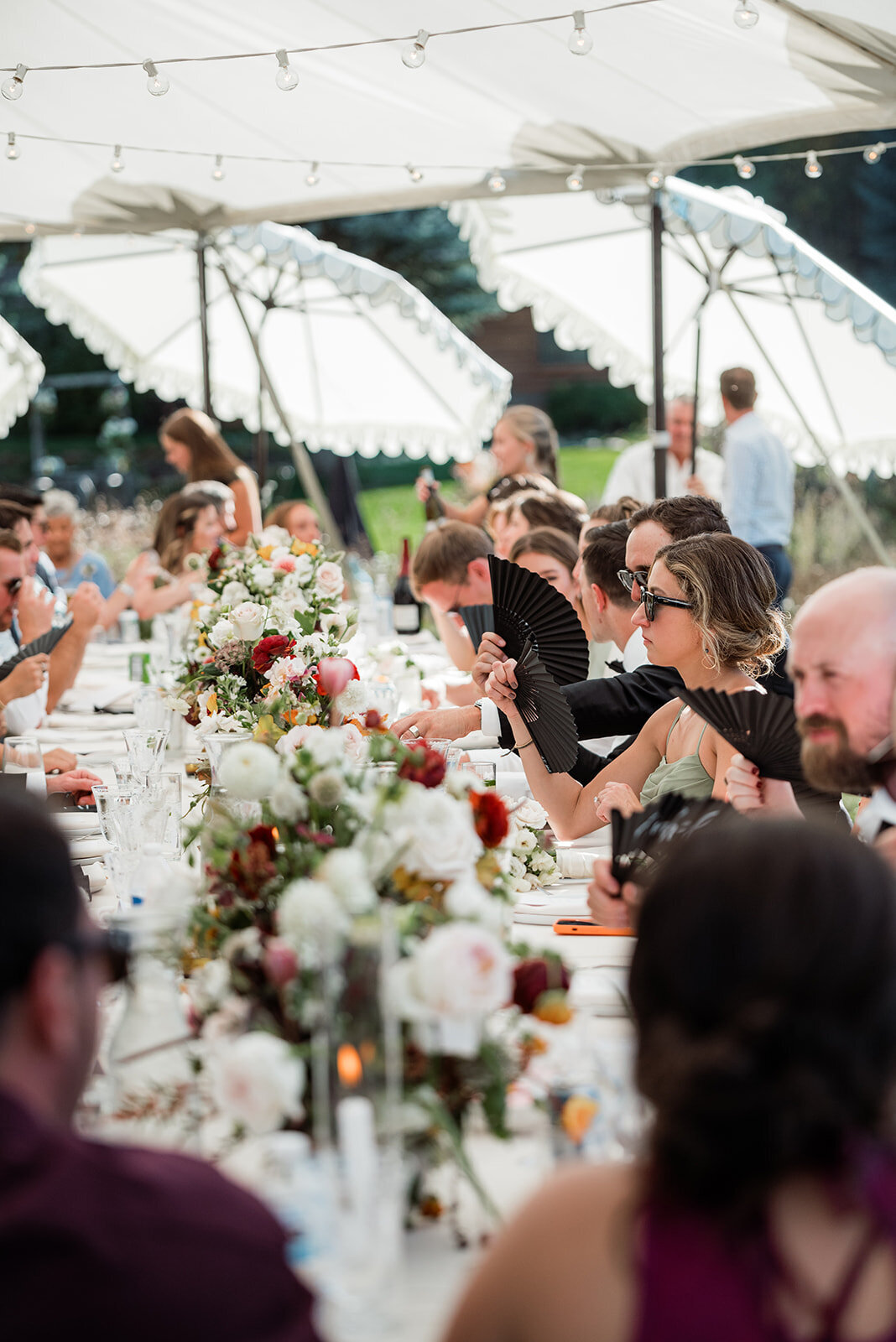 Guests seated at a wedding reception using black fans.