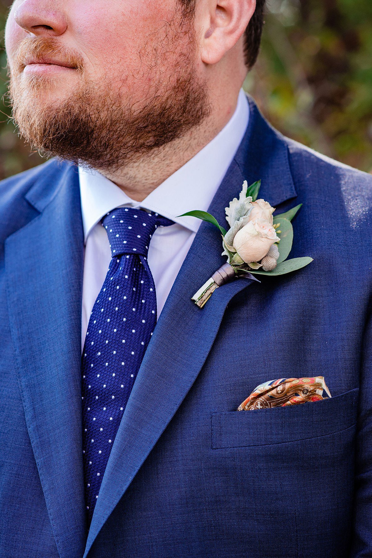 The groom, wearing a bright blue suit and blue swiss polkadot tie with an accenting pink pocket square. Detail photo of the groom's white rose boutonniere.