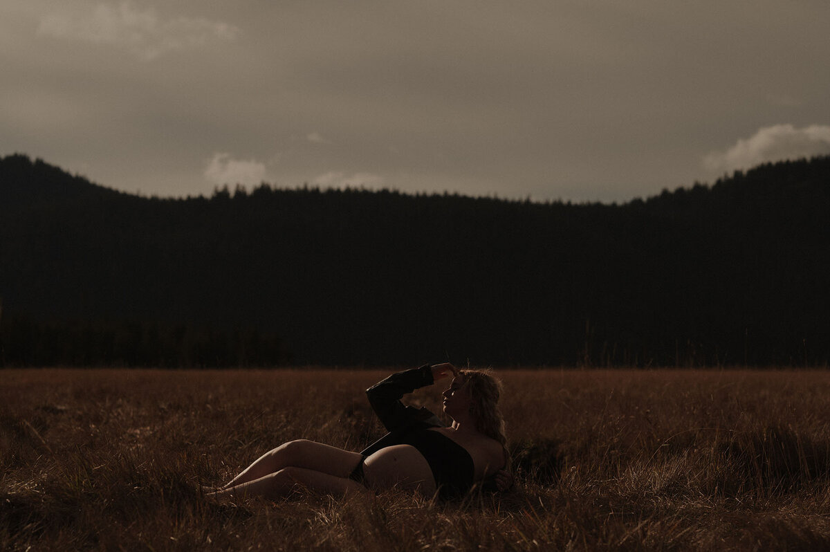 pregnant woman lays in a field of tall grass near Mt. Bachelor Oregon