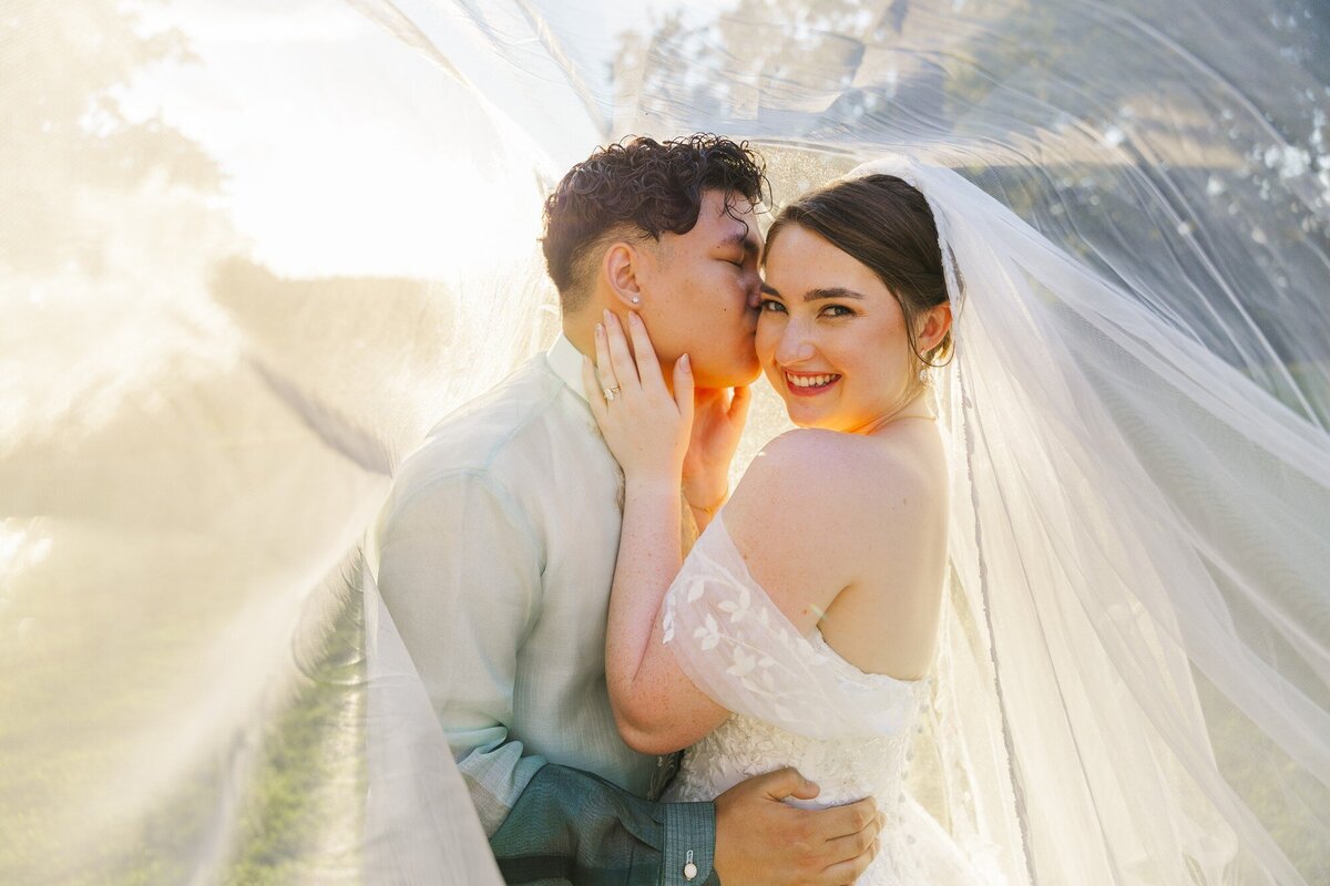 Golden hour Hudson Valley wedding portrait of a couple wrapped in a flowing veil