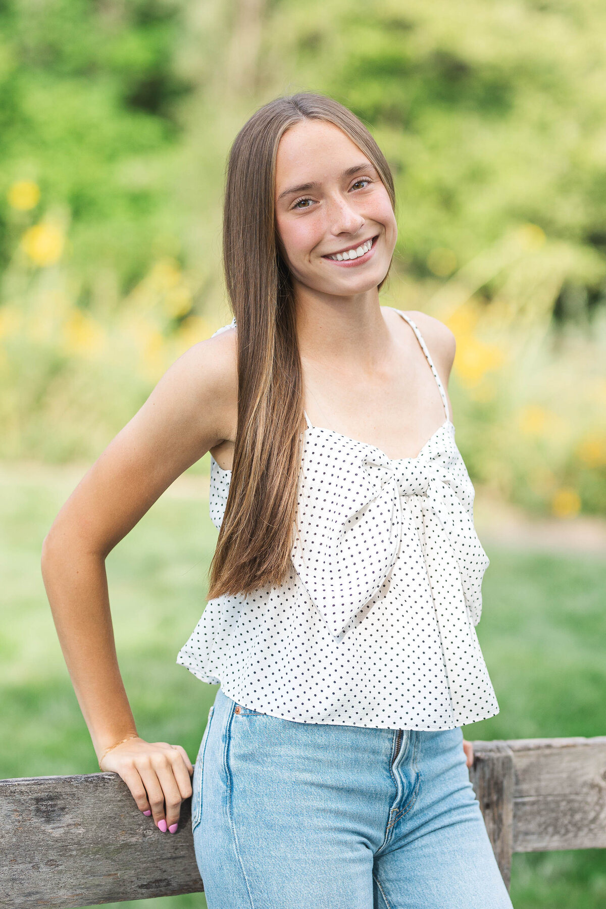 Outdoor senior photos at Inniswood Metro Gardens, with a high school senior posing by a wooden fence
