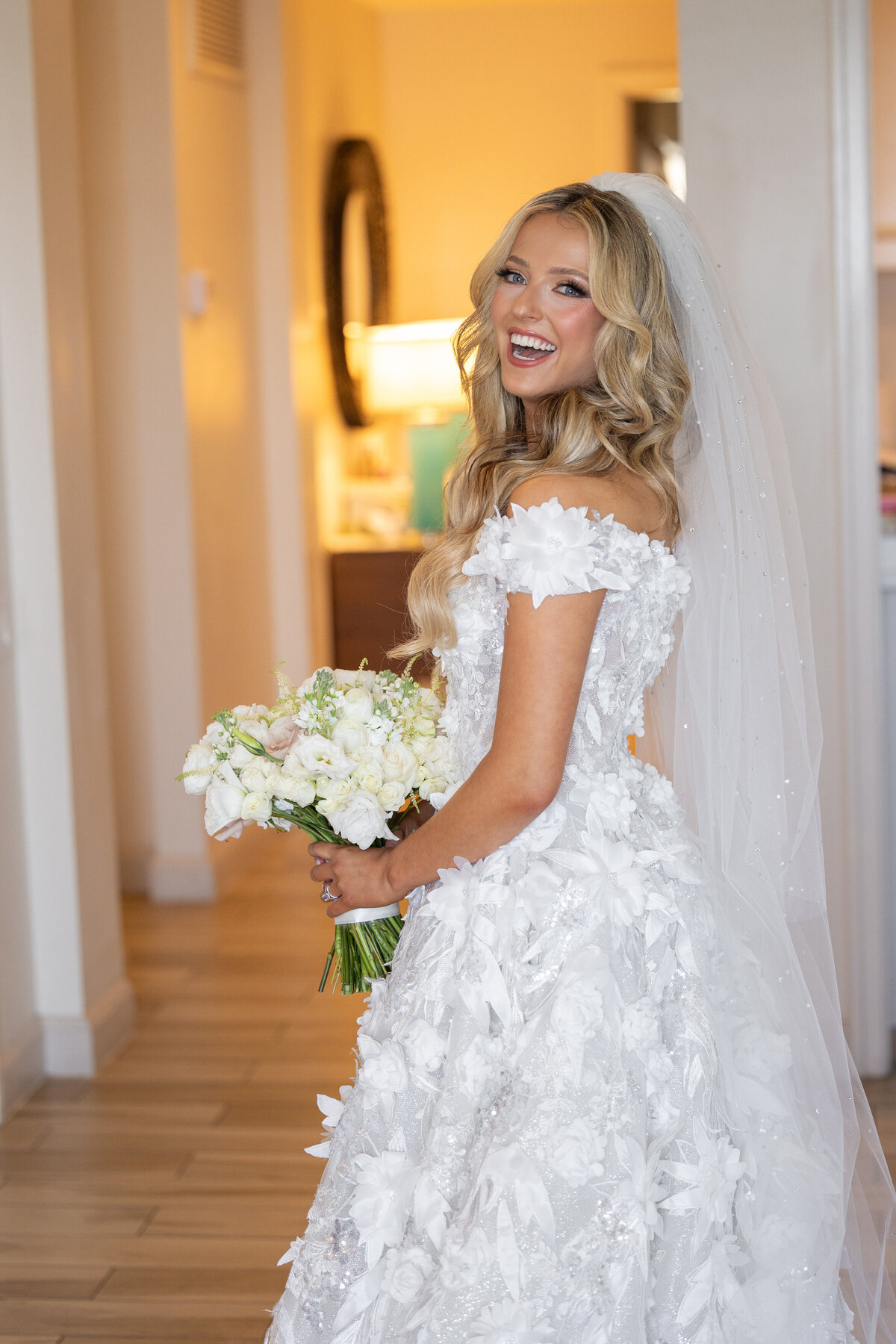 A bride looking over her should smiling as she holds a bouquet of flowers