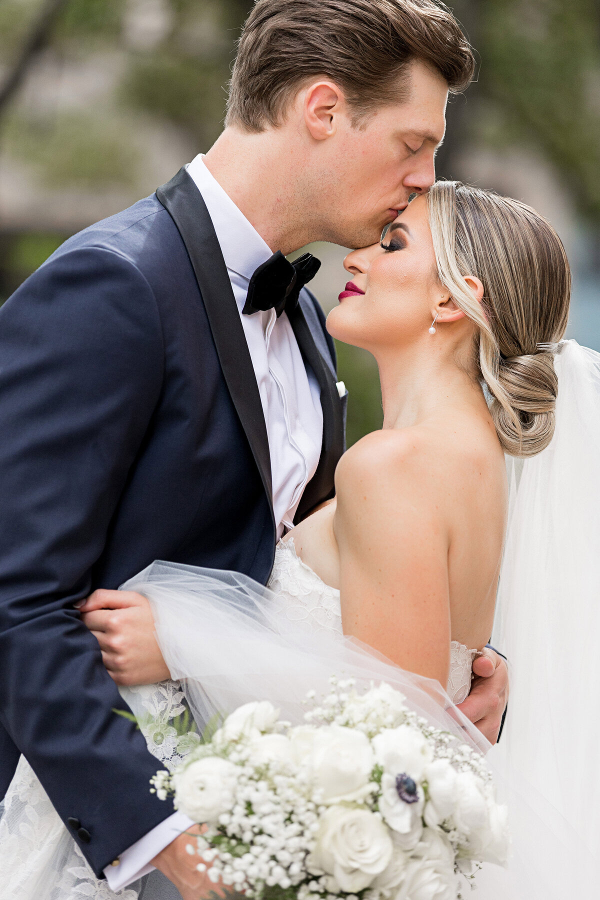 groom kissing bride on forehead before wedding ceremony