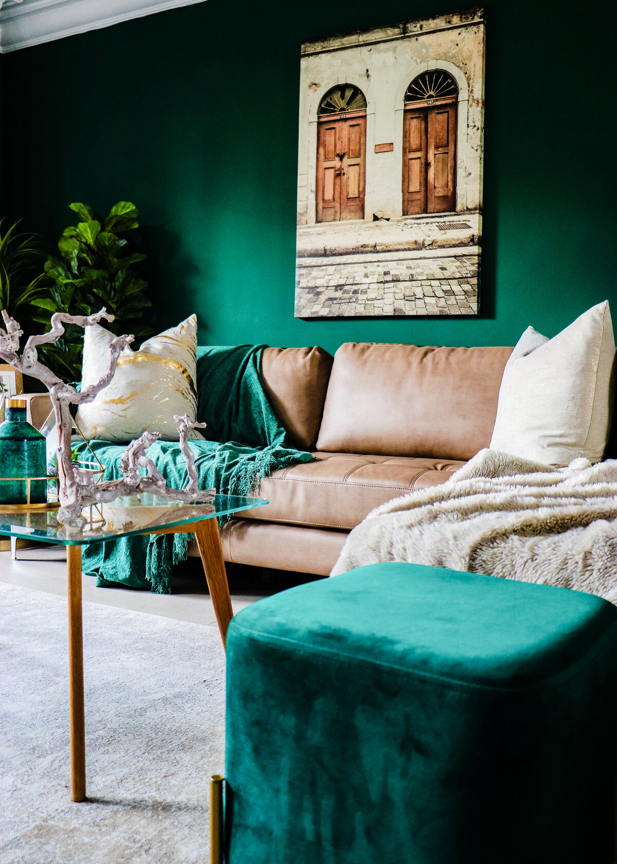 Dark green painted walls create a boho loung with a tan leather sofa and a beige throw.