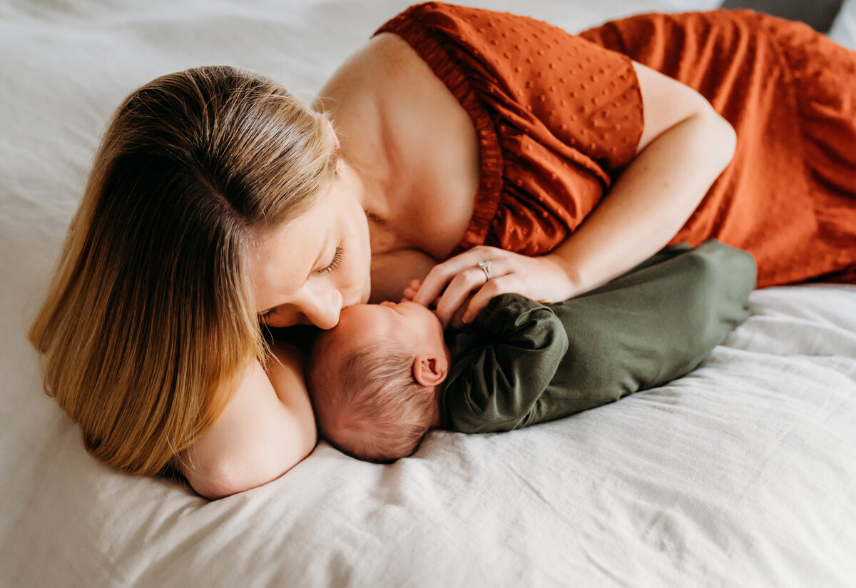Newborn Photographer, mother lays on bed admiring her newborn son