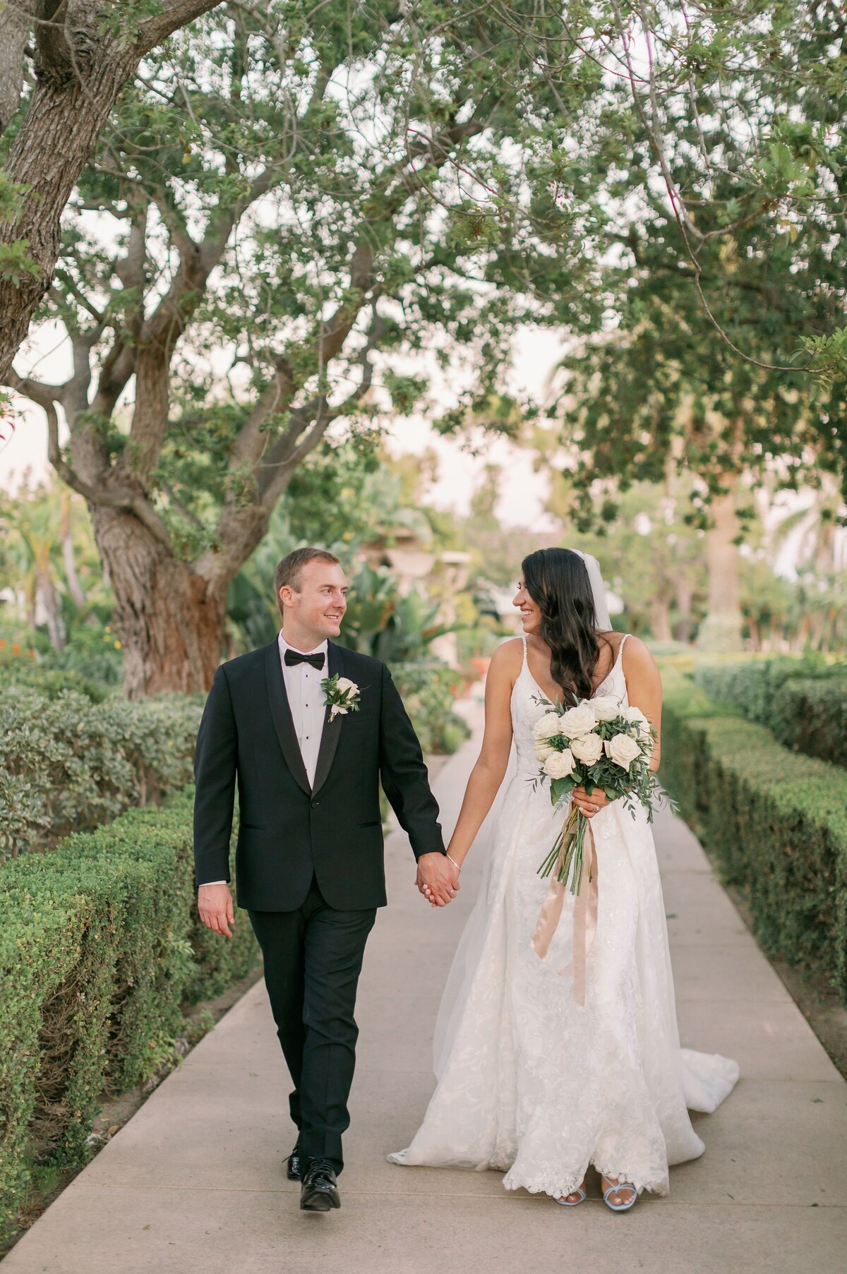 The newly weds walking down a garden path.