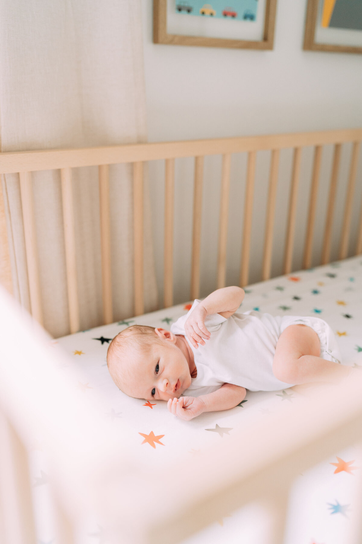 baby boy lies in crib with colorful star sheets