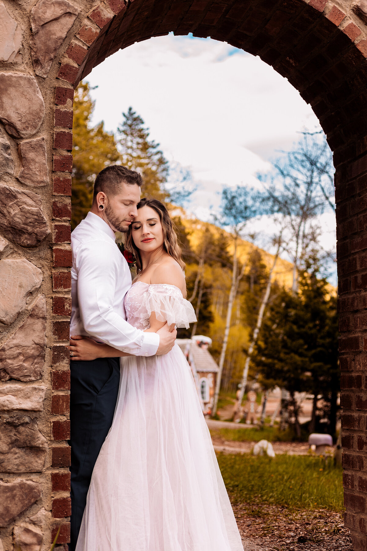 Bride and groom snuggle up under an archway at Charmed Resorts