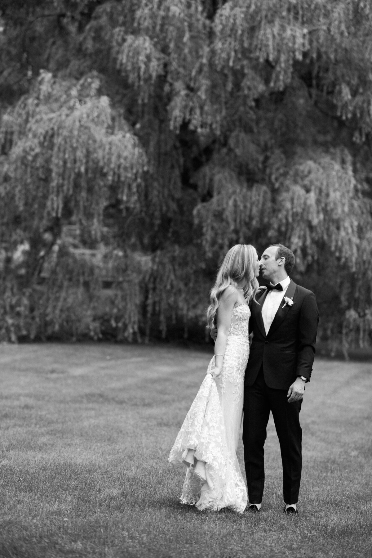 Bride and groom kiss in the grass