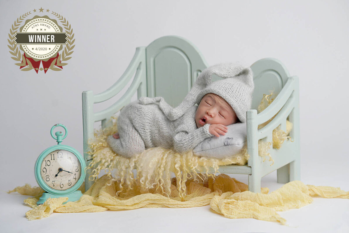 Newborn sleeping on a mini-bed for photoshoot