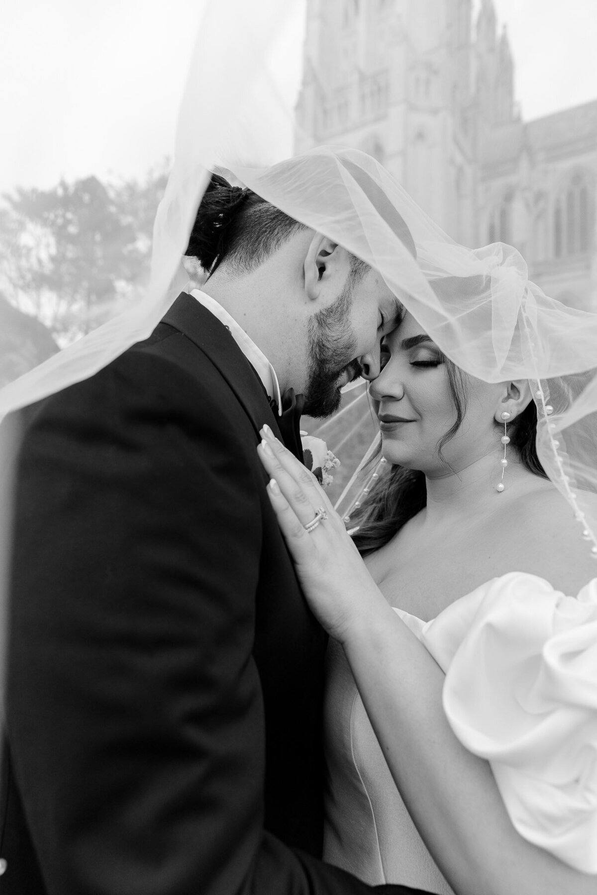 A bride and groom pose for a portrait. They're touching foreheads and both have their eyes closed. They in Raleigh NC.