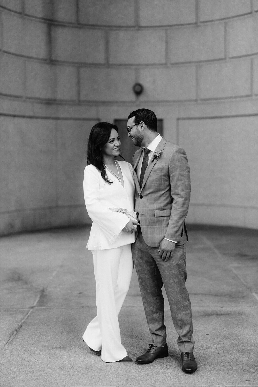 The bride and groom are standing close and happily looking at each other inside the NY City Hall. Image by Jenny Fu Studio