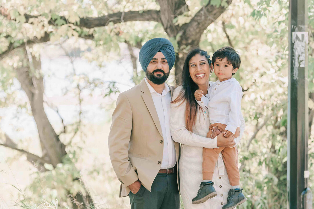 Mom and dad stand close together. Mom holds son. 