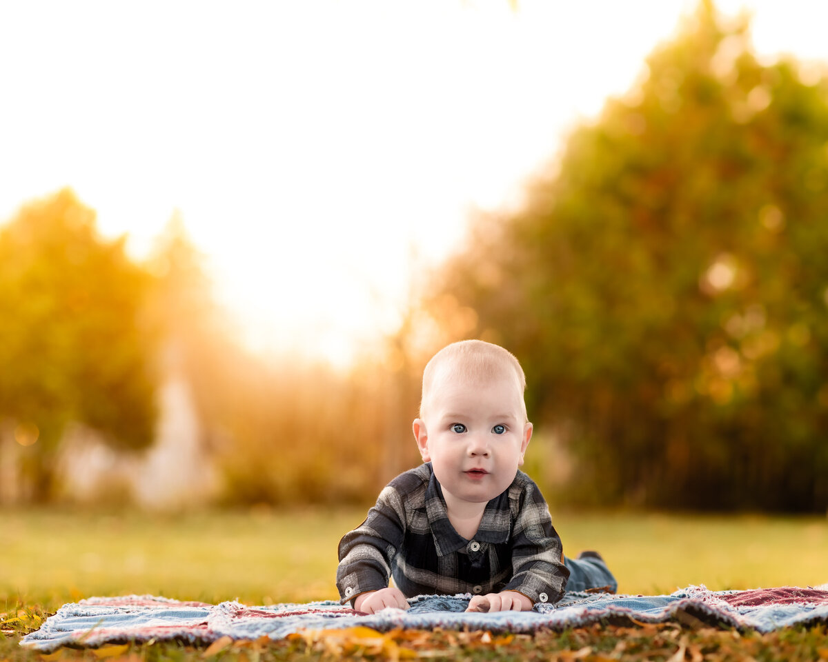 Golden-hour milestone session of a baby in Ayr, Ontario—styled in plaid and framed by rustic outdoor light and warmth.