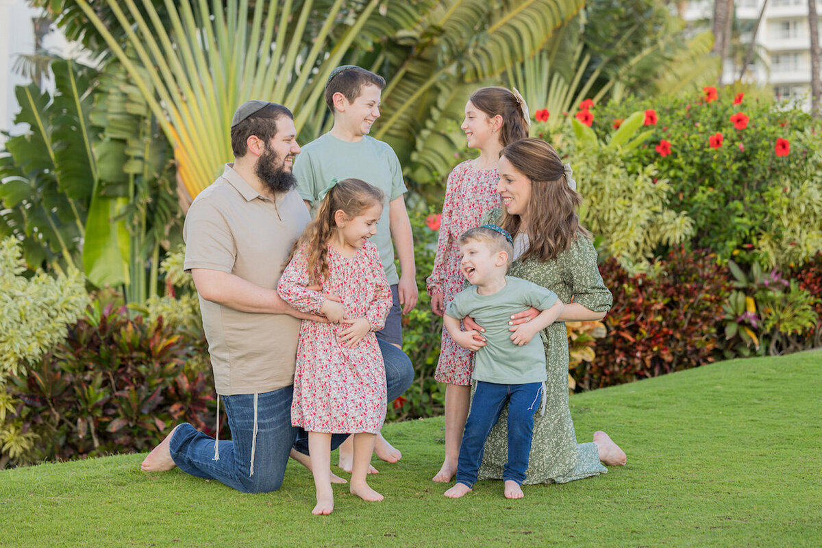 Mom and dad with their little ones in the grass, smiling and having fun