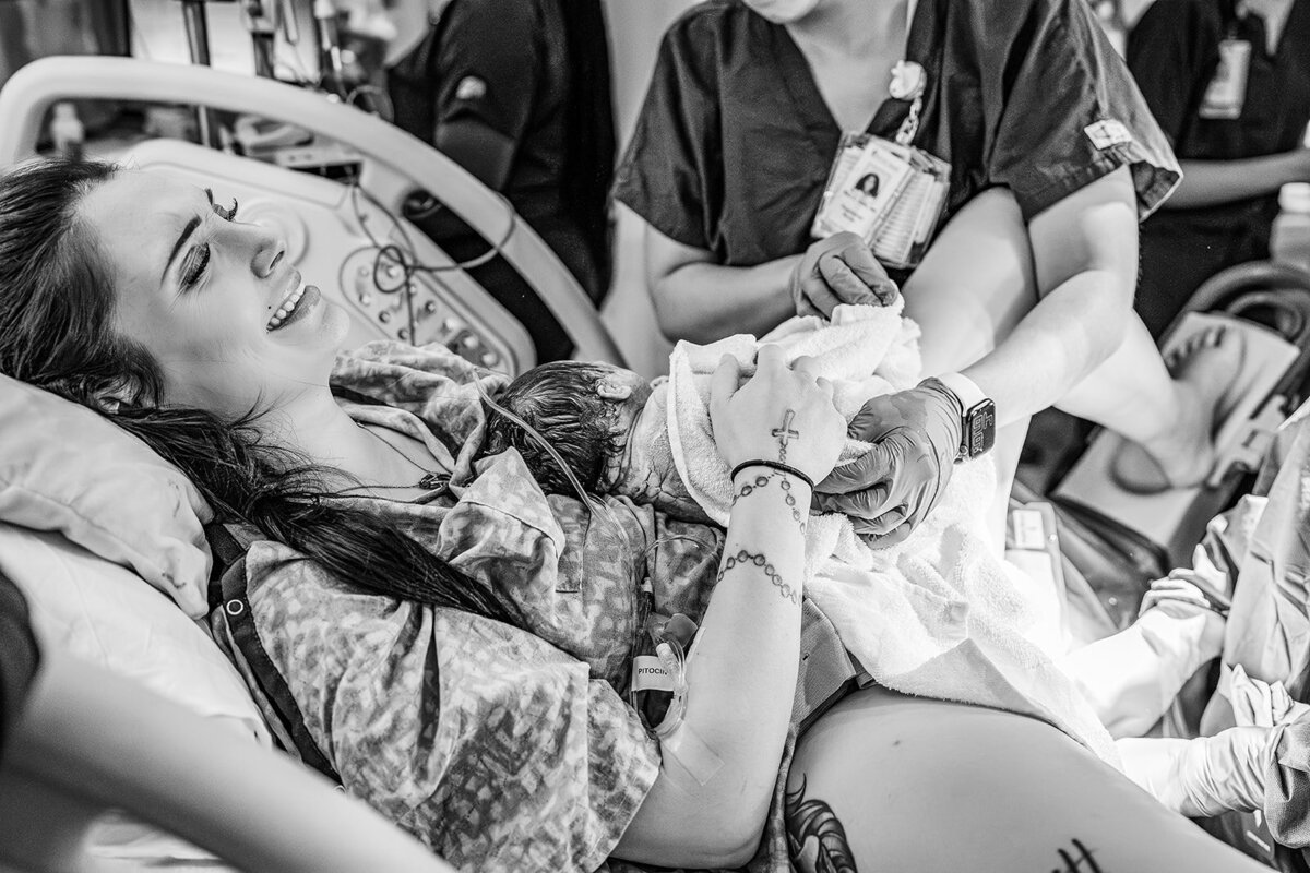 Raw and emotional black and white moment of a mother holding her newborn for the first time in a Charleston hospital birth session.