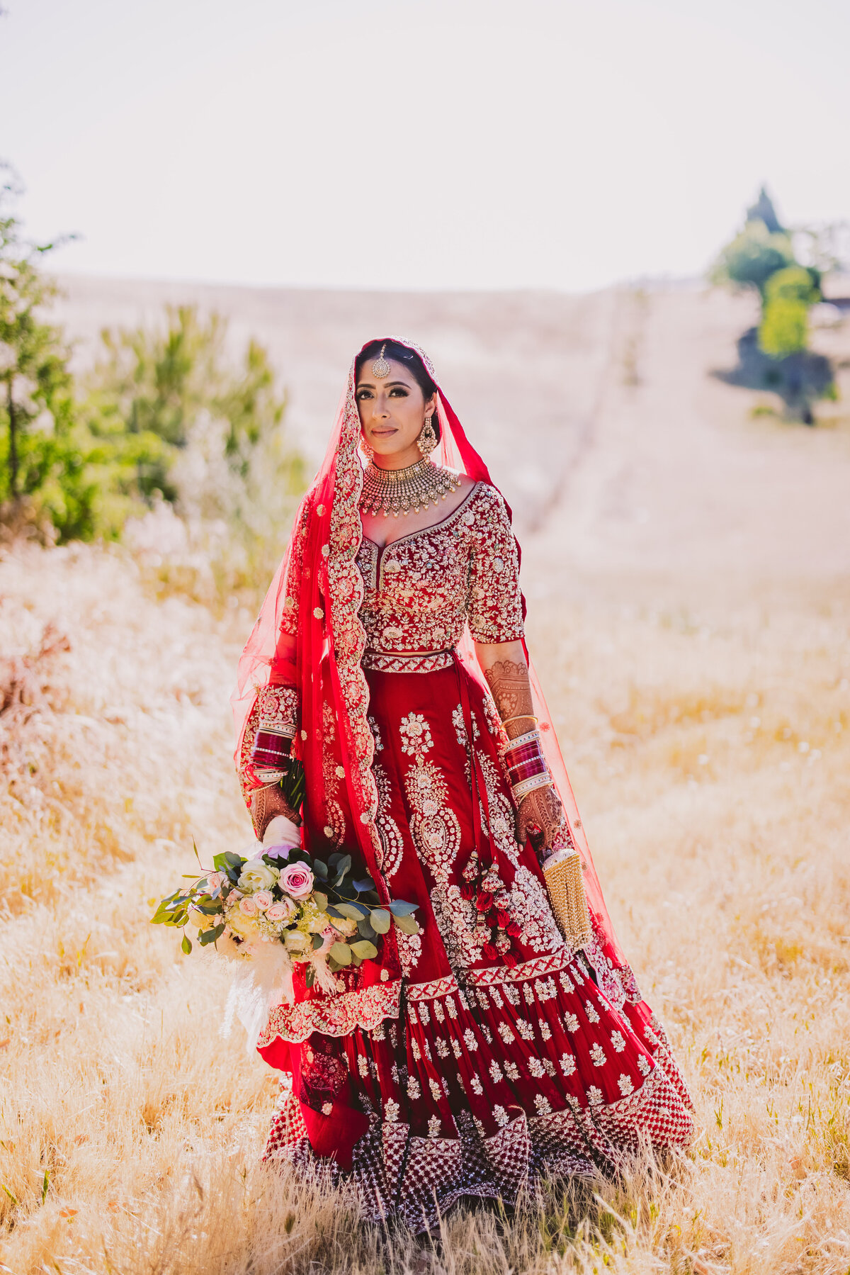 sikh bride wearing a red lehnga on an open field in sacramento california 