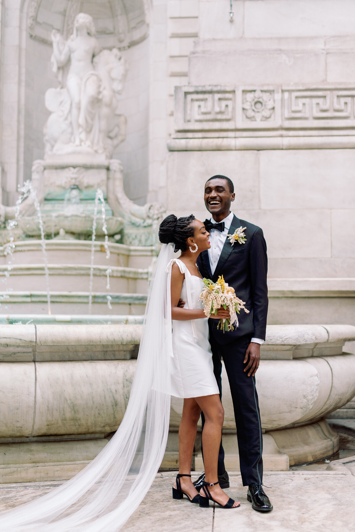 bride and groom laugh at NYC wedding with marble fountain in the background jaclyn watson events