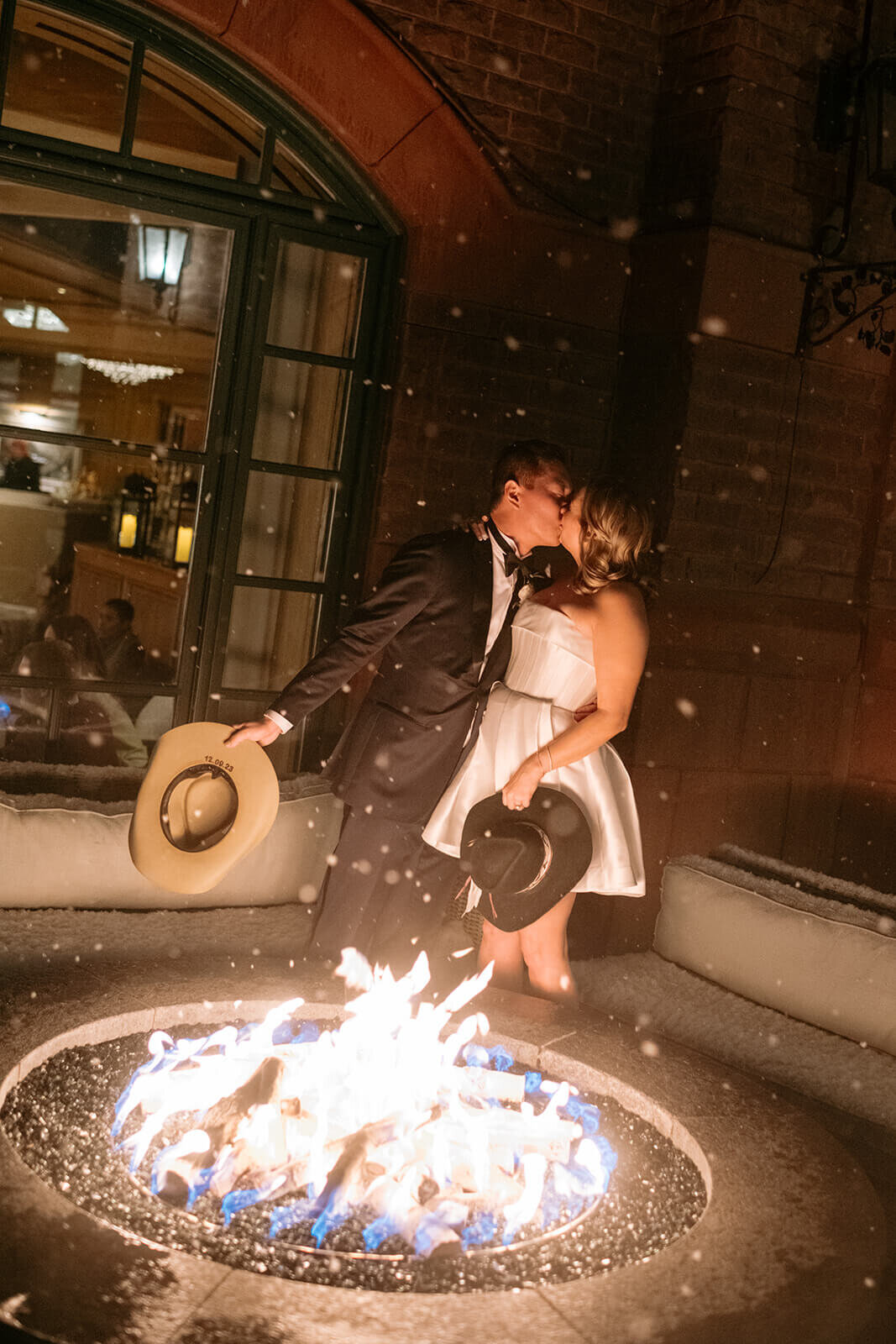 Bride and Groom share a kiss in the falling snow by the warm fire outside of the St. Regis Aspen wedding venue.
