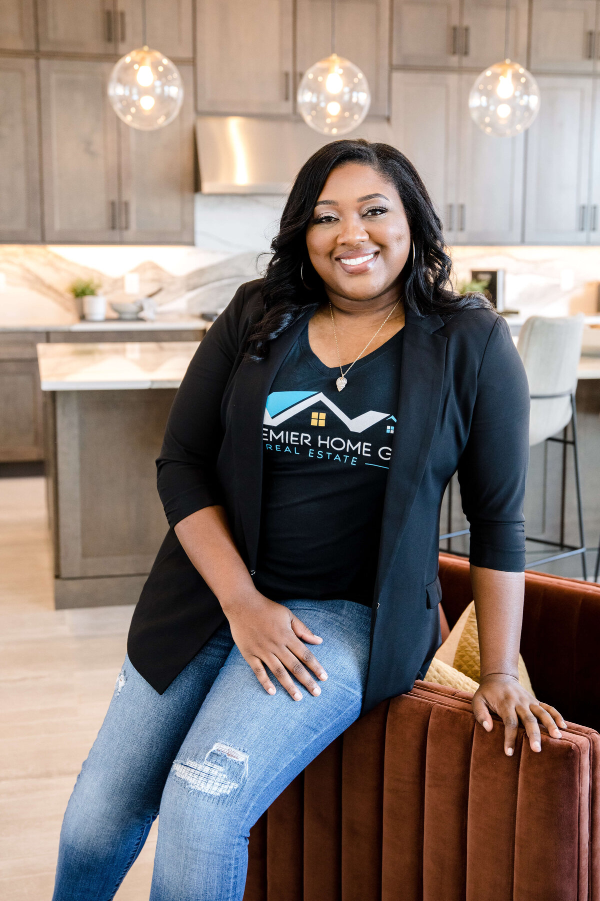 brand photography with woman sitting on a brown sofa wearing jeans and a blazer posing for a brand photo with commercial photographers