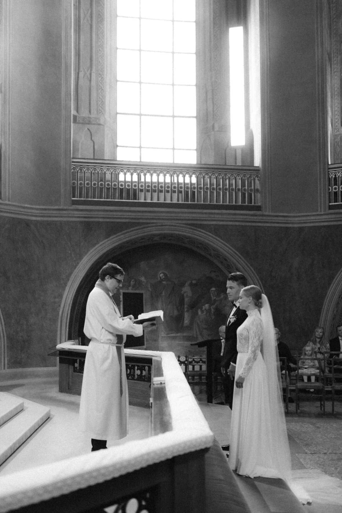 Documentary wedding photograph of a wedding ceremony. Bride and groom are by the altar.