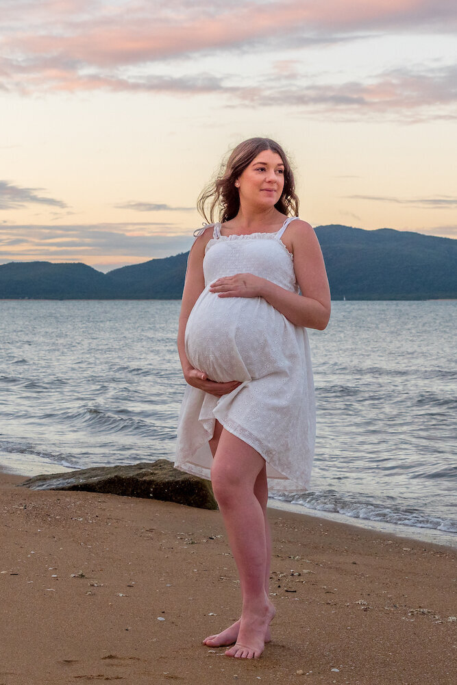 pregnant woman at the beach holding baby belly at sunset - Townsville Maternity Photography by Jamie Simmons